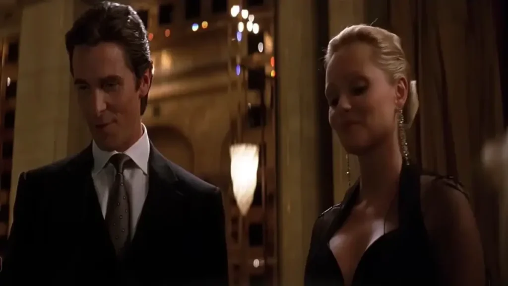 Dark cinematic scene showing a sharply dressed man and woman in an elegant interior setting from a noir-style superhero film