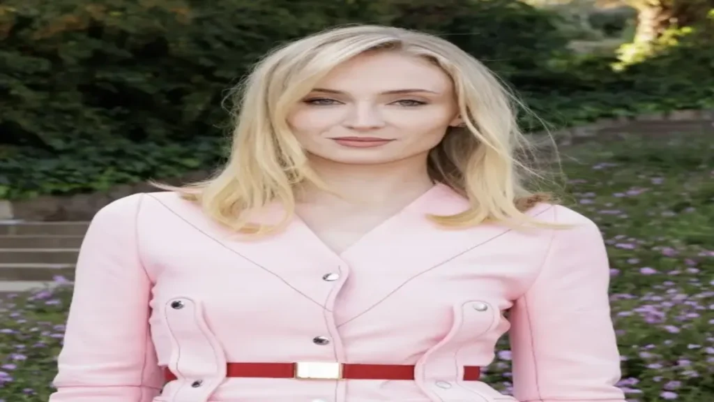 Sophie Turner Gets Held Hostage in an Armed Robbery: Woman in a tense moment wearing a pink jacket during a dramatic crime scene