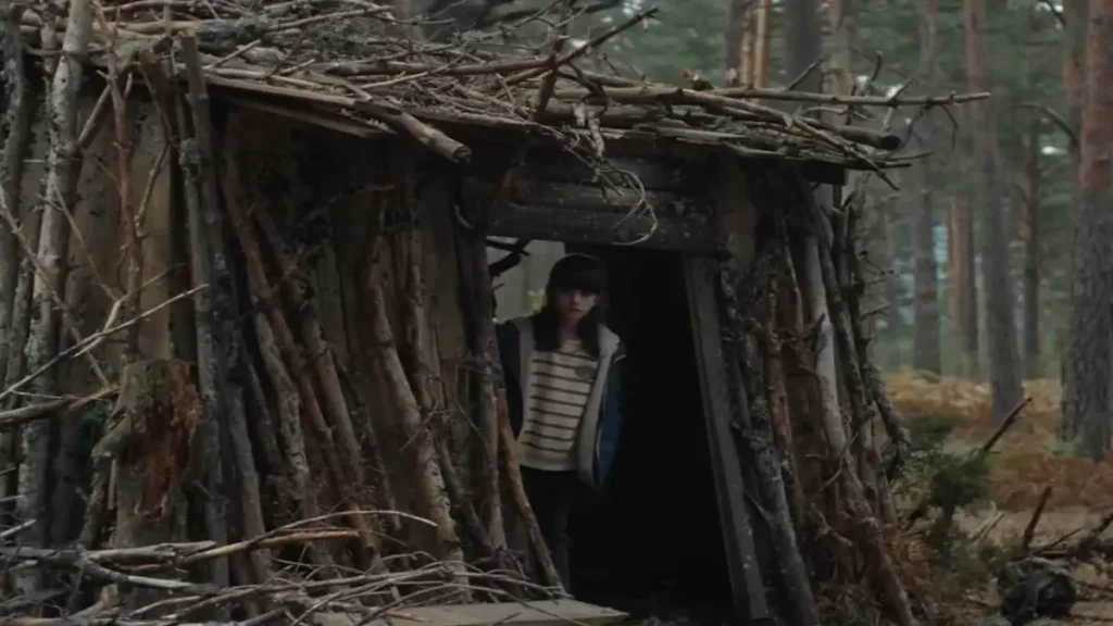 Person standing inside a handmade wooden shelter in a forest from Netflix’s Firebreak trailer