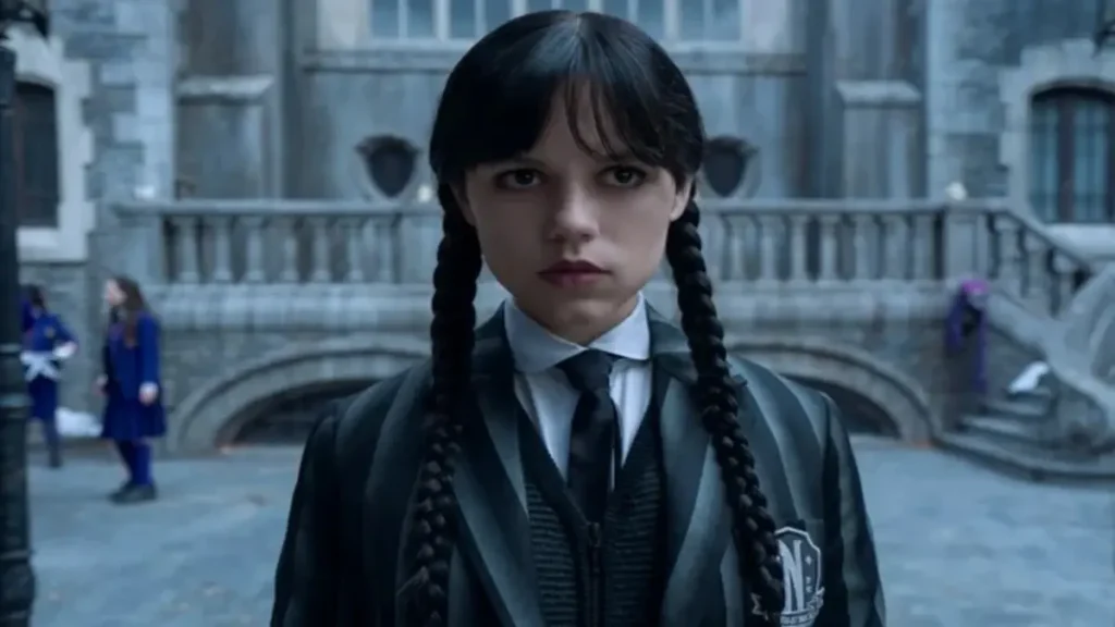 Wednesday Season 3 Cast Announcement & Updates Wednesday Addams standing in front of Nevermore Academy in Season 3 Netflix teaser