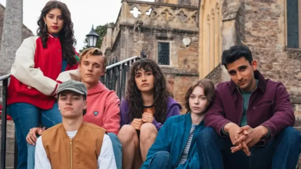 Cast of A Good Girl’s Guide to Murder Season 2 sitting together in a tense outdoor scene