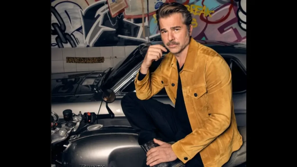 Engin Altan Düzyatan posing beside a motorcycle ahead of TRT’s espionage drama series Espiyonaj