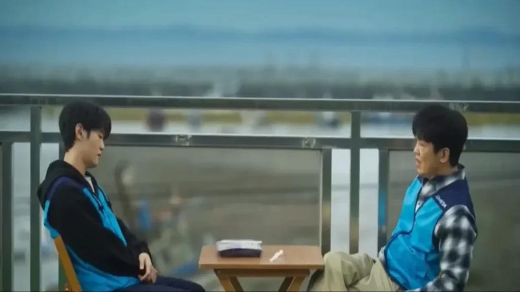 Two workers sitting silently at a rooftop table in the Fifties Professionals trailer scene.