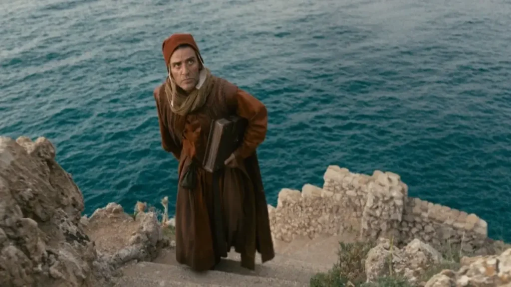 Oscar Isaac in In the Hand of Dante official Netflix trailer standing beside the sea in a dramatic medieval-inspired scene.