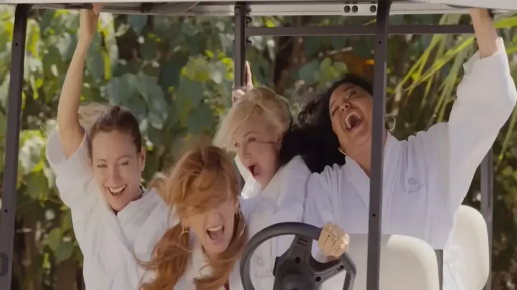 Four women in spa robes laughing and screaming while riding a golf cart in the Spa Weekend official trailer.