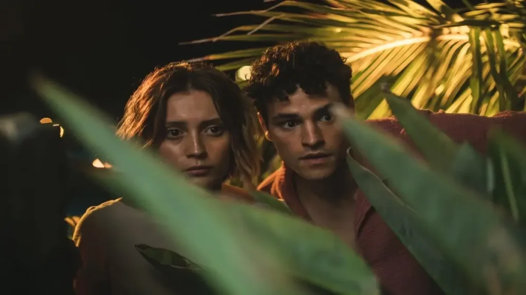Oasis Netflix official trailer scene showing two characters hiding among tropical plants during a suspenseful moment