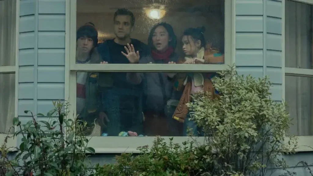 Greta Lee and Wagner Moura in The Last House Netflix trailer looking through a window during a tense scene.